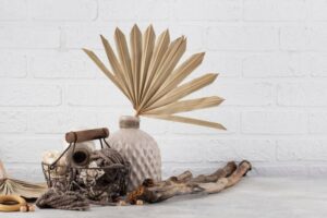 A decorative arrangement featuring a beige vase with a fan-shaped plant.