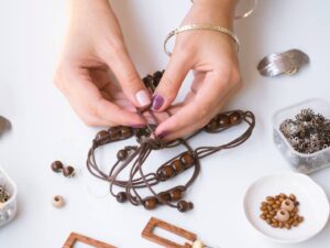 Hands assembling a beaded necklace.