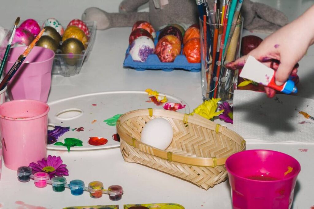 A messy art table features colorful Easter eggs.