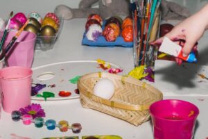 A messy art table features colorful Easter eggs.