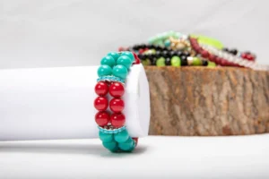 A vibrant turquoise and red beaded bracelet displayed on a white surface.