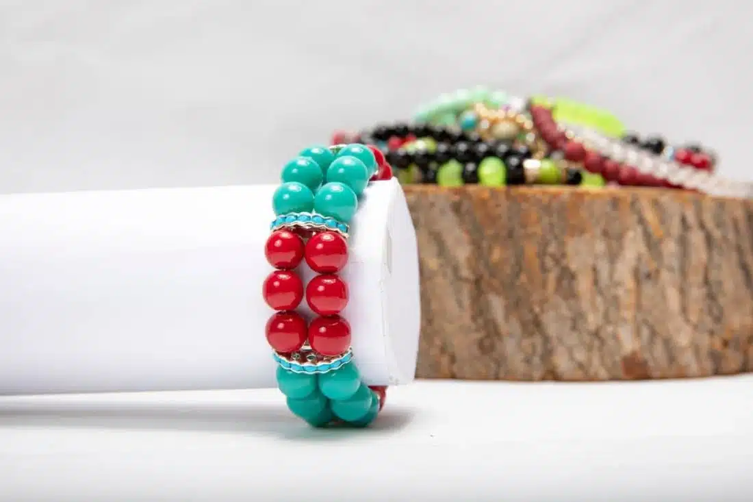A vibrant turquoise and red beaded bracelet displayed on a white surface.
